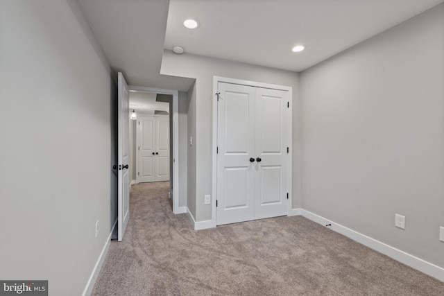 unfurnished bedroom with carpet floors, baseboards, recessed lighting, and a closet