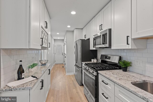 kitchen featuring stainless steel appliances, light wood-type flooring, recessed lighting, white cabinets, and light stone counters