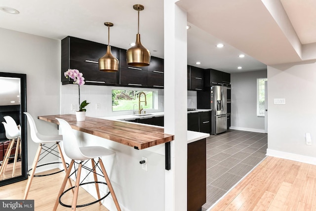 2432 S Culpeper St, Arlington, VA 22206 - kitchen with dark cabinets, wood counters, stainless steel fridge, a breakfast bar area, and modern cabinets