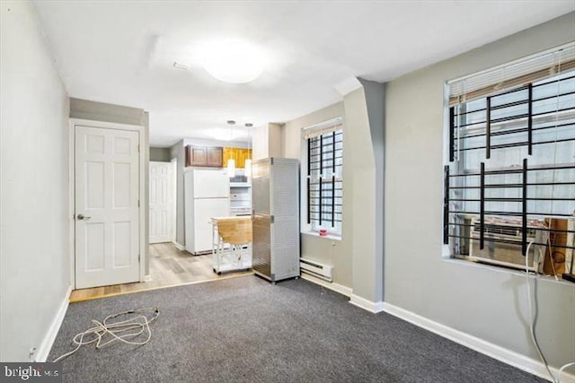 carpeted spare room with baseboards and a baseboard heating unit