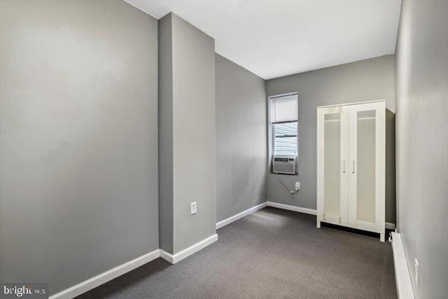 unfurnished bedroom with baseboards, dark carpet, and cooling unit