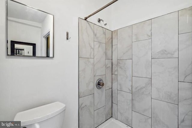 full bath featuring tiled shower and toilet
