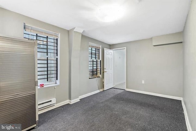 unfurnished room featuring a baseboard radiator, baseboards, and dark carpet