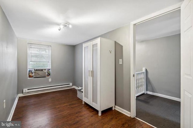 spare room with baseboard heating, wood finished floors, baseboards, and cooling unit