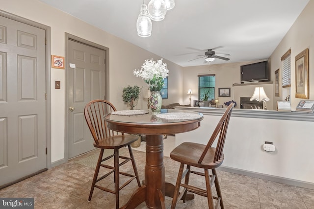 dining room with ceiling fan, light tile patterned flooring, and baseboards
