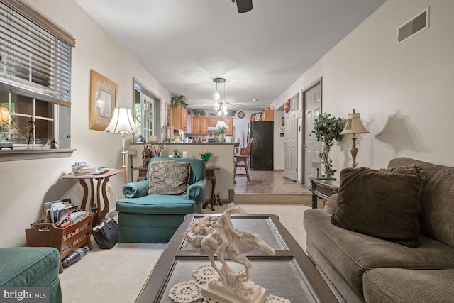 living room featuring light colored carpet, a chandelier, and ceiling fan
