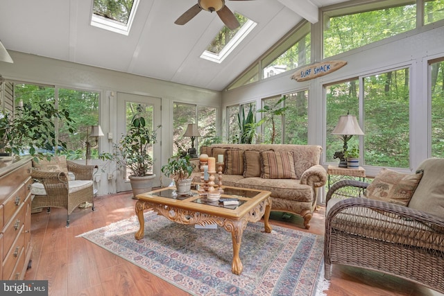 sunroom / solarium featuring a skylight, healthy amount of natural light, wood finished floors, beam ceiling, and high vaulted ceiling