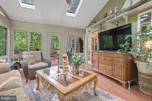 living area with a skylight, lofted ceiling, and light wood-style flooring