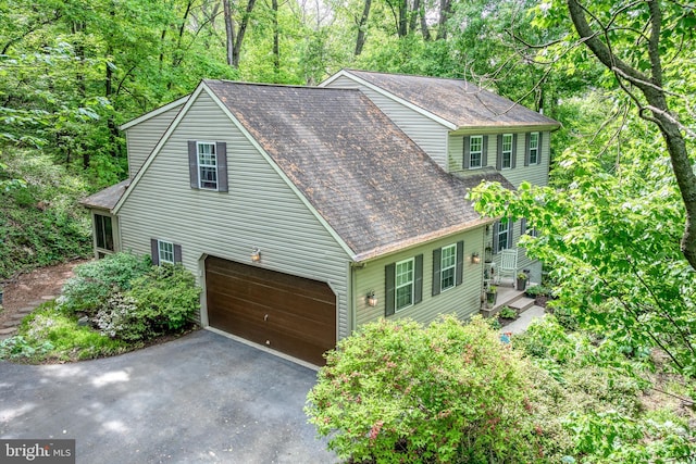 view of property exterior with asphalt driveway and a shingled roof