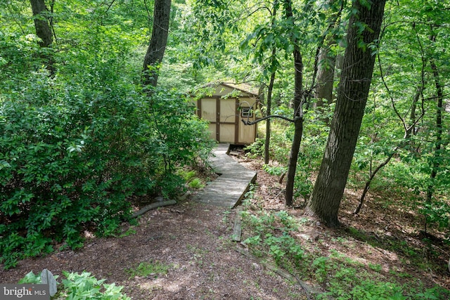 view of yard with a shed, an outbuilding, and a forest view