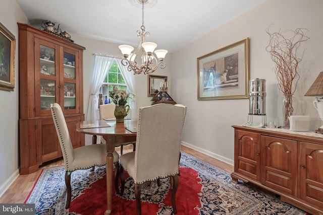 dining area with a chandelier, light wood-type flooring, and baseboards