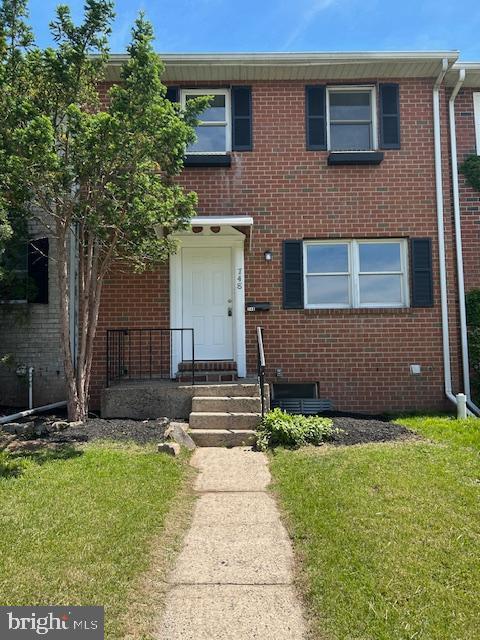 multi unit property featuring a front lawn and brick siding