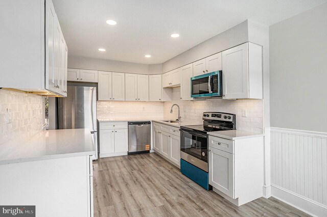748 Jefferson St, Red Hill, PA 18076 - kitchen with stainless steel appliances, light wood-style flooring, a wainscoted wall, light countertops, and white cabinets