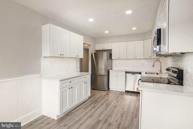 748 Jefferson St, Red Hill, PA 18076 - kitchen featuring stainless steel appliances, a sink, light wood-style floors, white cabinets, and wainscoting