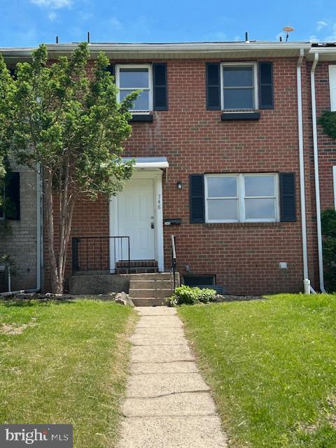 view of property featuring brick siding and a front yard
