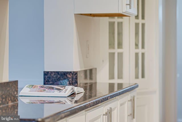 detailed view of white cabinetry and dark countertops