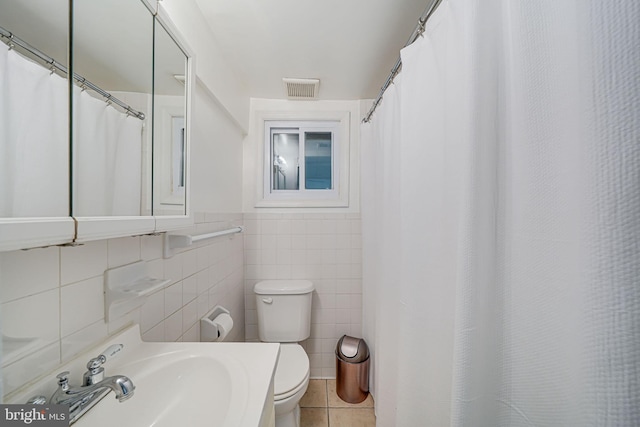 bathroom featuring tile walls, toilet, a sink, tile patterned flooring, and curtained shower