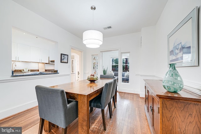 dining space with light wood-type flooring and baseboards