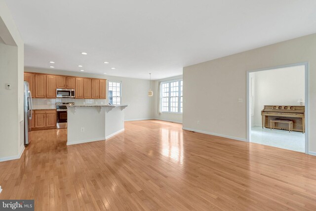 42522 Neighborly Ln, Chantilly, VA 20152 - kitchen featuring stainless steel appliances, open floor plan, a kitchen bar, light wood finished floors, and recessed lighting