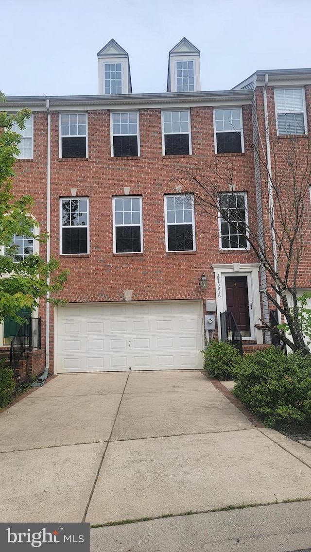 multi unit property featuring concrete driveway, an attached garage, and brick siding