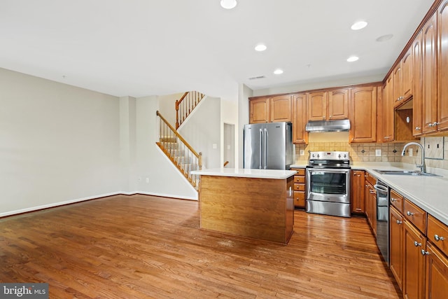 10016 Love Song Ct, Laurel, MD 20723 - kitchen featuring stainless steel appliances, a sink, a kitchen island, wood finished floors, and under cabinet range hood