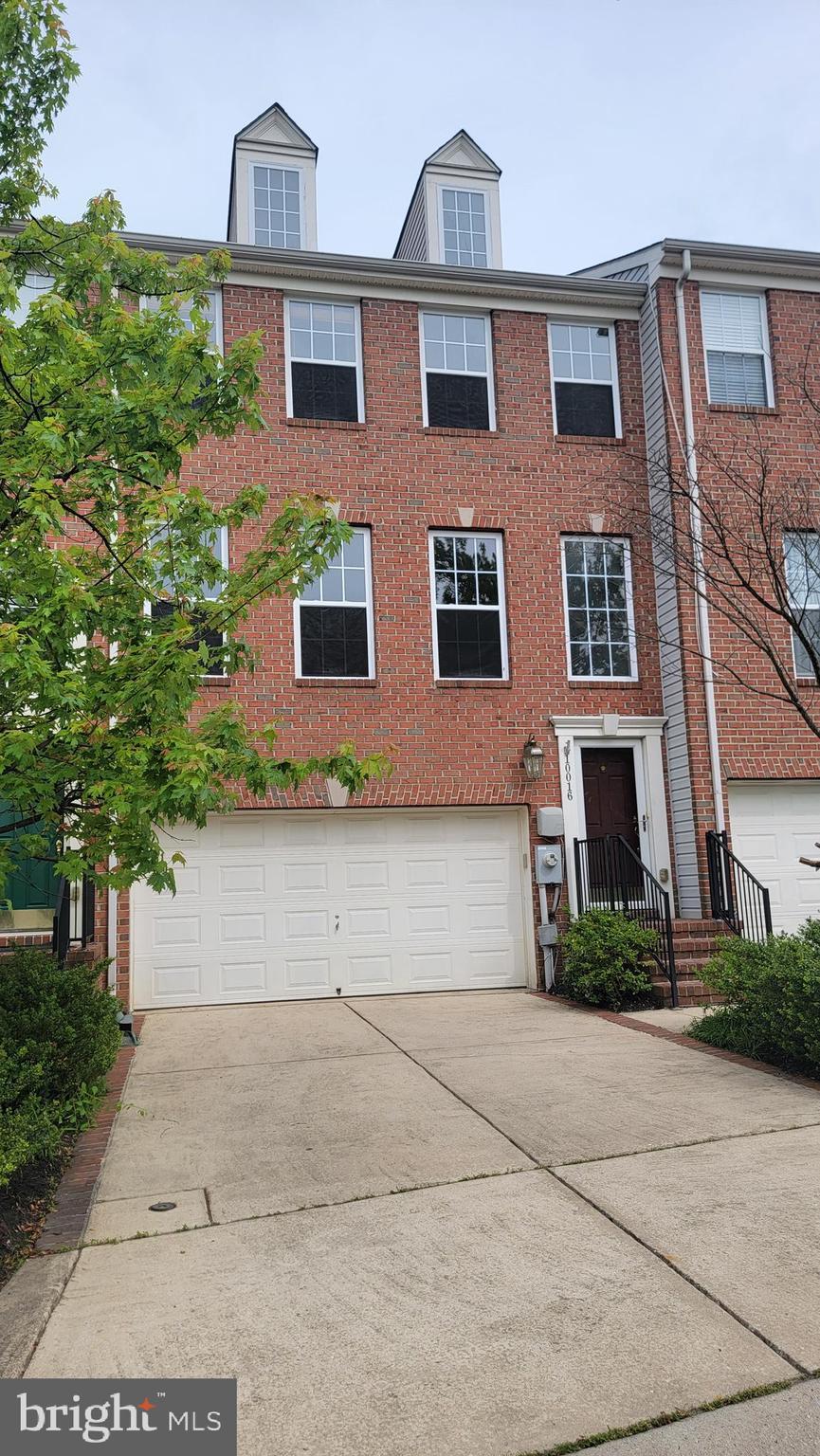 multi unit property with concrete driveway, a garage, and brick siding