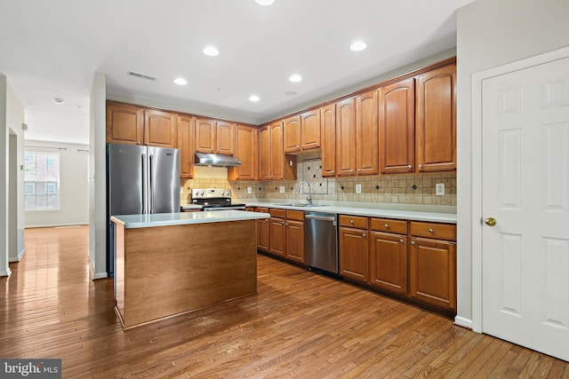 10016 Love Song Ct, Laurel, MD 20723 - kitchen with appliances with stainless steel finishes, under cabinet range hood, decorative backsplash, hardwood / wood-style floors, and a sink