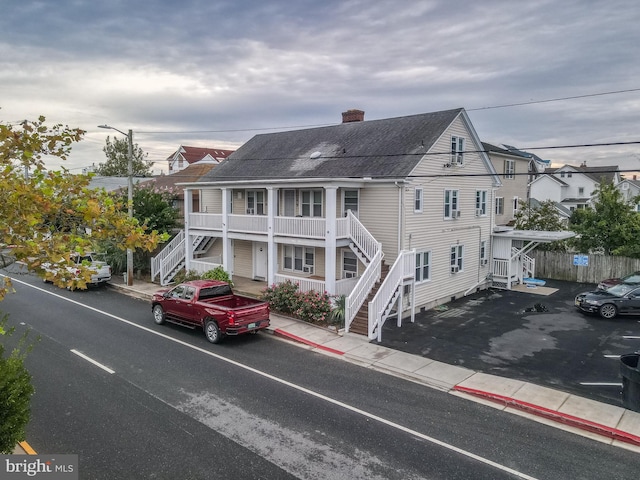 1004 Philadelphia Ave, Ocean City, MD 21842 - view of front of house featuring stairs, a chimney, covered porch, roof with shingles, and fence