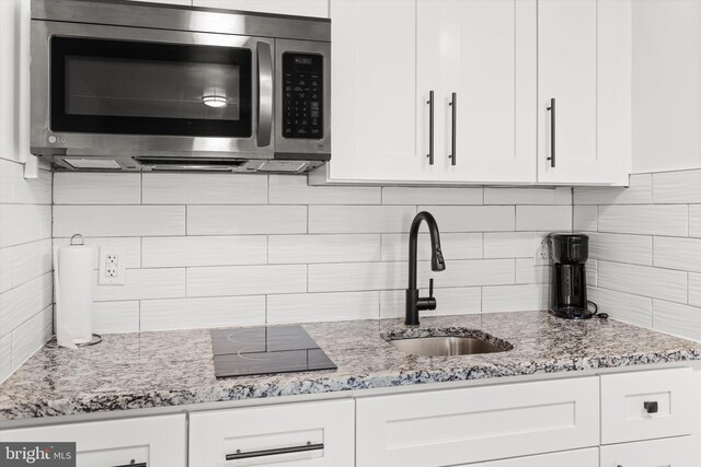 1004 Philadelphia Ave, Ocean City, MD 21842 - kitchen with stainless steel microwave, a sink, tasteful backsplash, and light stone countertops
