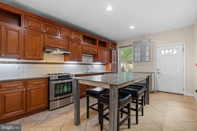 kitchen with gas stove, a sink, under cabinet range hood, open shelves, and decorative backsplash
