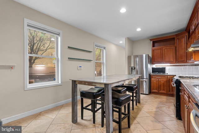 kitchen featuring stainless steel refrigerator with ice dispenser, range, plenty of natural light, backsplash, and recessed lighting