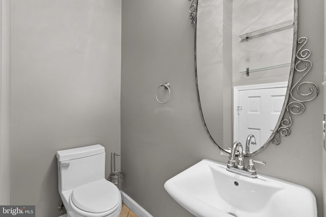 half bath featuring a sink, toilet, and baseboards