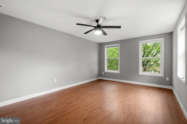 unfurnished room featuring wood finished floors, baseboards, and ceiling fan