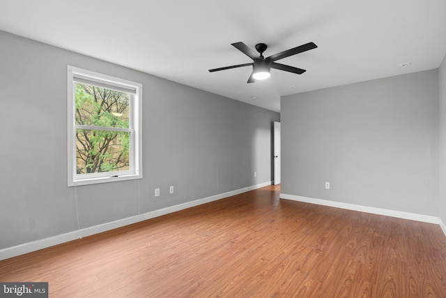spare room with baseboards, wood finished floors, and ceiling fan