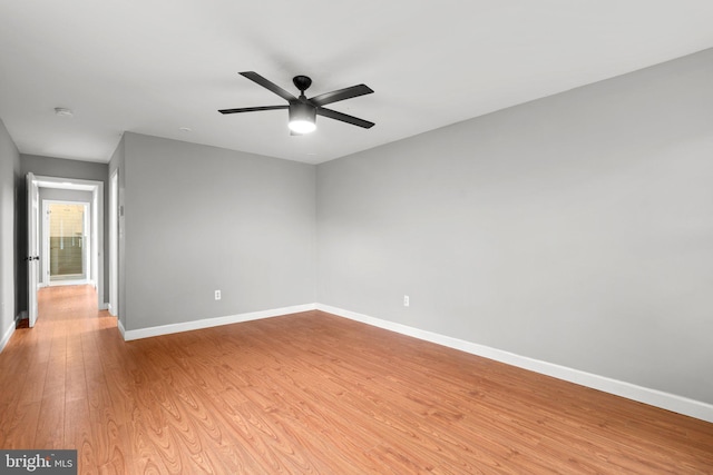 spare room with baseboards, light wood-style flooring, and ceiling fan