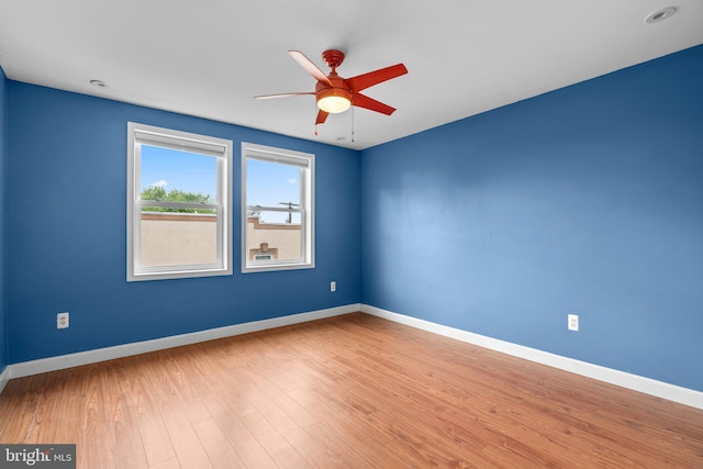 spare room with ceiling fan, wood finished floors, and baseboards