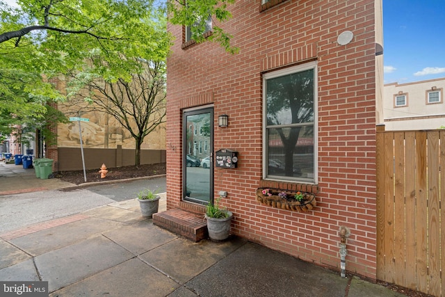 property entrance featuring brick siding and fence
