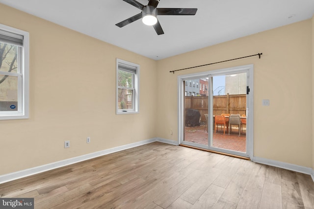 unfurnished room with wood finished floors, a ceiling fan, and baseboards
