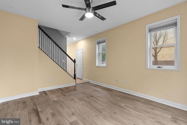 unfurnished living room with ceiling fan, light wood-style flooring, and baseboards