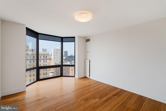 2018 Walnut St Unit 19Gh, Philadelphia, PA 19103 - empty room featuring a wall of windows, a city view, wood finished floors, and baseboards
