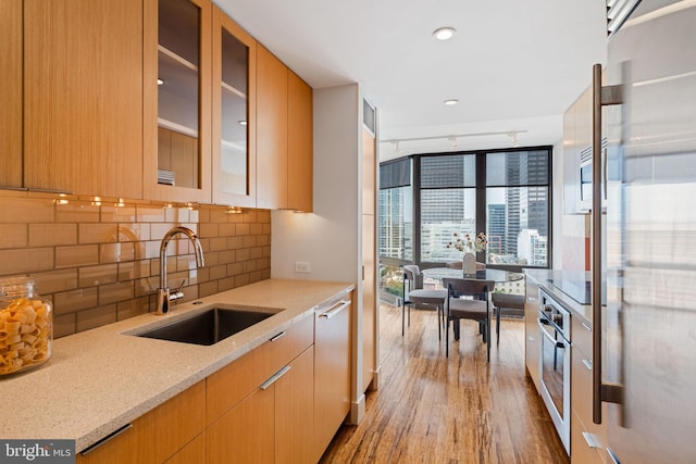 2018 Walnut St Unit 19Gh, Philadelphia, PA 19103 - kitchen with a sink, appliances with stainless steel finishes, wood finished floors, light stone countertops, and backsplash