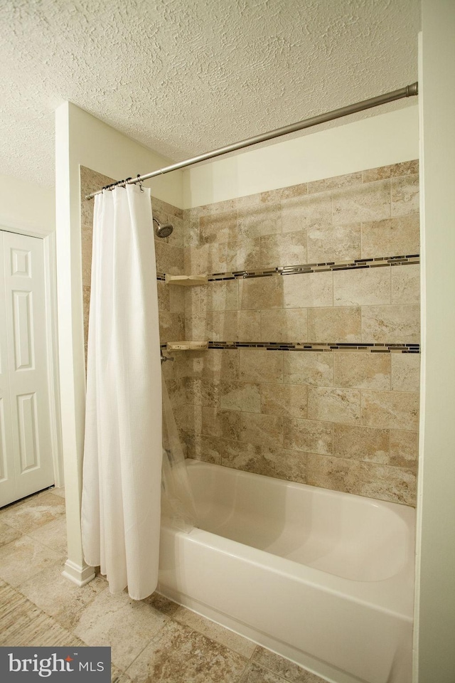 bathroom with a textured ceiling and shower / bathtub combination with curtain