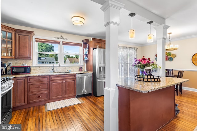 kitchen with appliances with stainless steel finishes, a sink, dark wood finished floors, ornate columns, and decorative backsplash