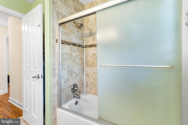 full bathroom with combined bath / shower with glass door, wood finished floors, and baseboards
