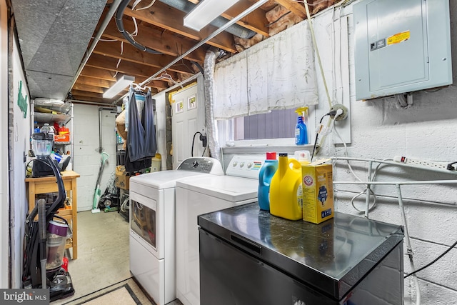 clothes washing area with electric panel, separate washer and dryer, and concrete block wall
