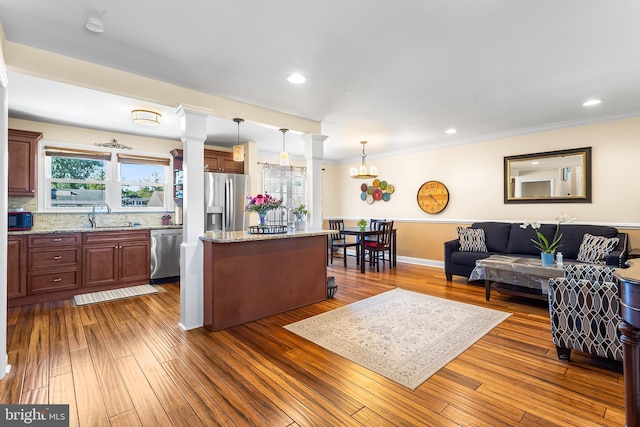 living area featuring plenty of natural light, dark wood-style floors, ornamental molding, recessed lighting, and decorative columns