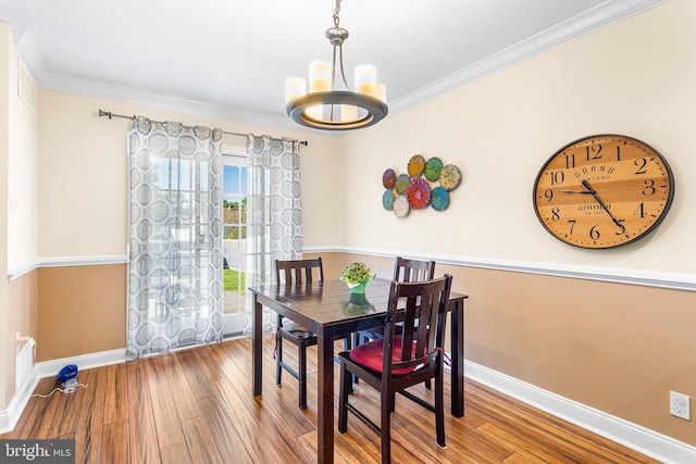 dining space featuring baseboards, a chandelier, wood-type flooring, and ornamental molding