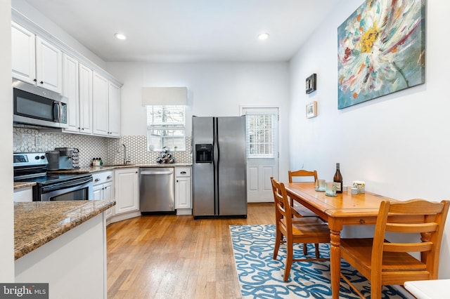 2113 Montrose St, Philadelphia, PA 19146 - kitchen with appliances with stainless steel finishes, white cabinetry, a sink, decorative backsplash, and light wood-style floors