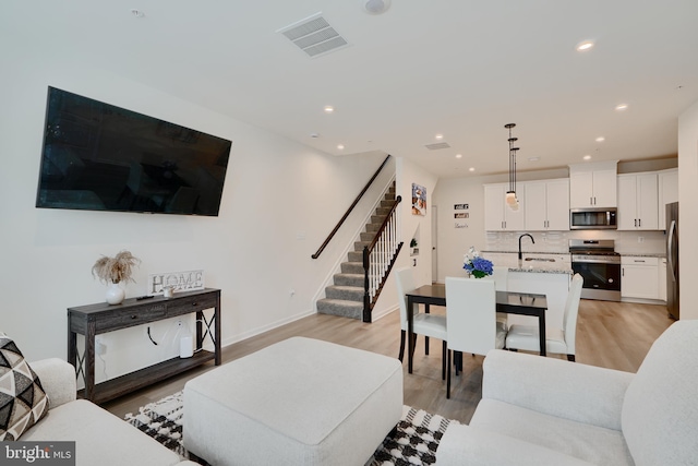 living room with stairway, light wood-style floors, recessed lighting, and baseboards