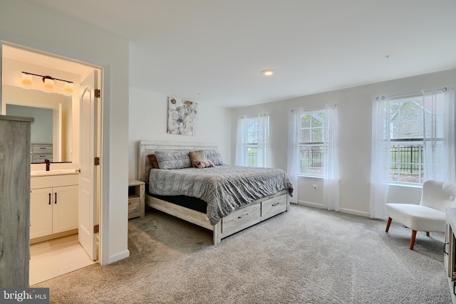 bedroom with light carpet, baseboards, connected bathroom, a sink, and recessed lighting